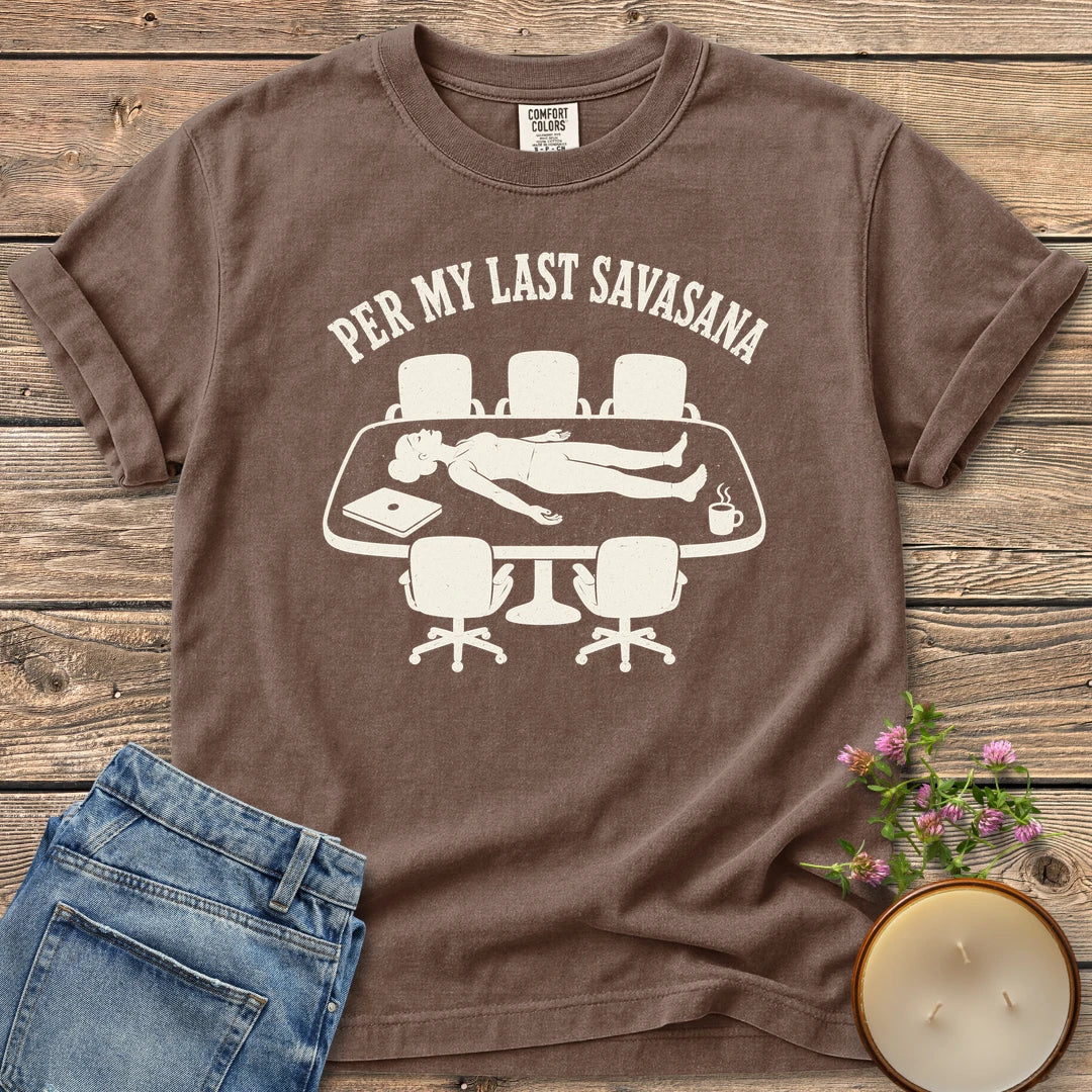 Per My Last Savasana t-shirt, a person lying flat on a conference table under Per My Last Savasana, on an Espresso Comfort Colors tee