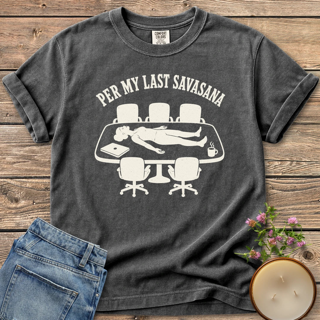 Per My Last Savasana t-shirt, a person lying flat on a conference table under Per My Last Savasana, on a Pepper Comfort Colors tee