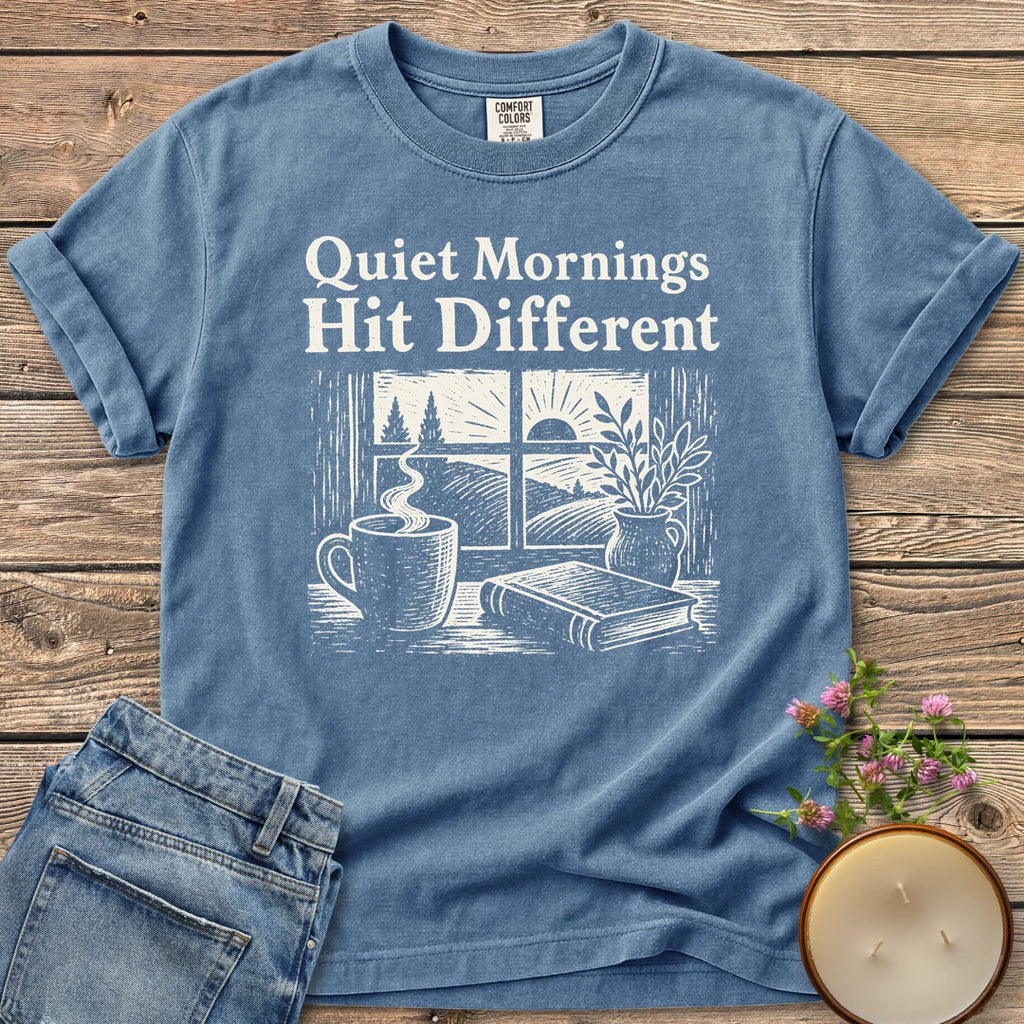 Quiet Mornings Hit Different t-shirt, Quiet Mornings Hit Different over a woodcut of coffee, a book and a window at sunrise, on a Blue Jean Comfort Colors tee
