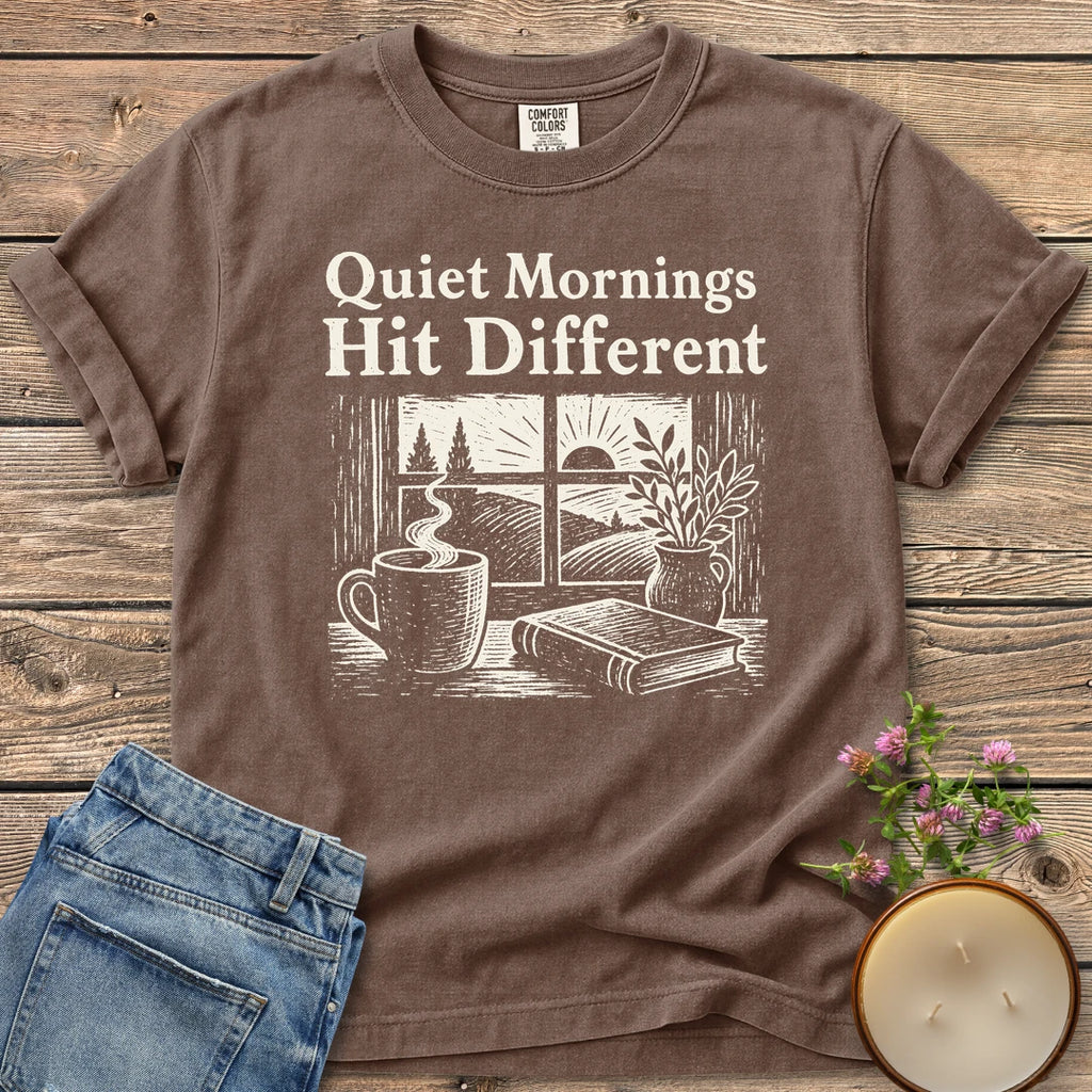 Quiet Mornings Hit Different t-shirt, Quiet Mornings Hit Different over a woodcut of coffee, a book and a window at sunrise, on an Espresso Comfort Colors tee
