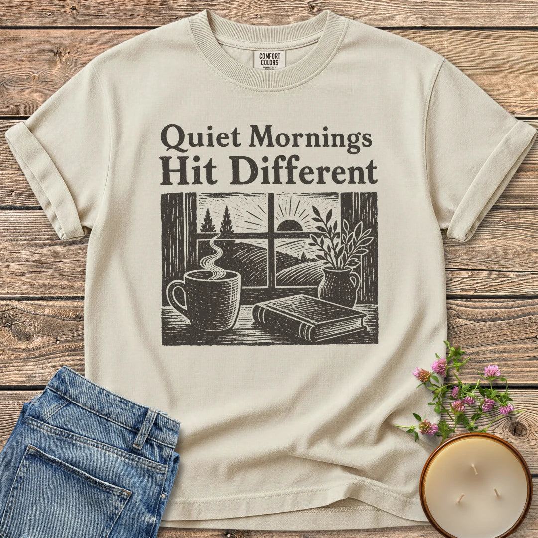 Quiet Mornings Hit Different t-shirt, Quiet Mornings Hit Different over a woodcut of coffee, a book and a window at sunrise, on an Ivory Comfort Colors tee
