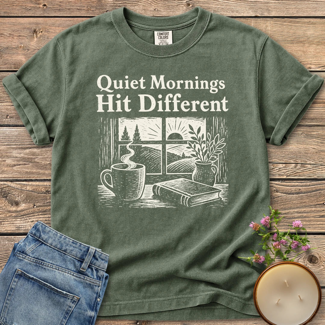 Quiet Mornings Hit Different t-shirt, Quiet Mornings Hit Different over a woodcut of coffee, a book and a window at sunrise, on a Moss Comfort Colors tee