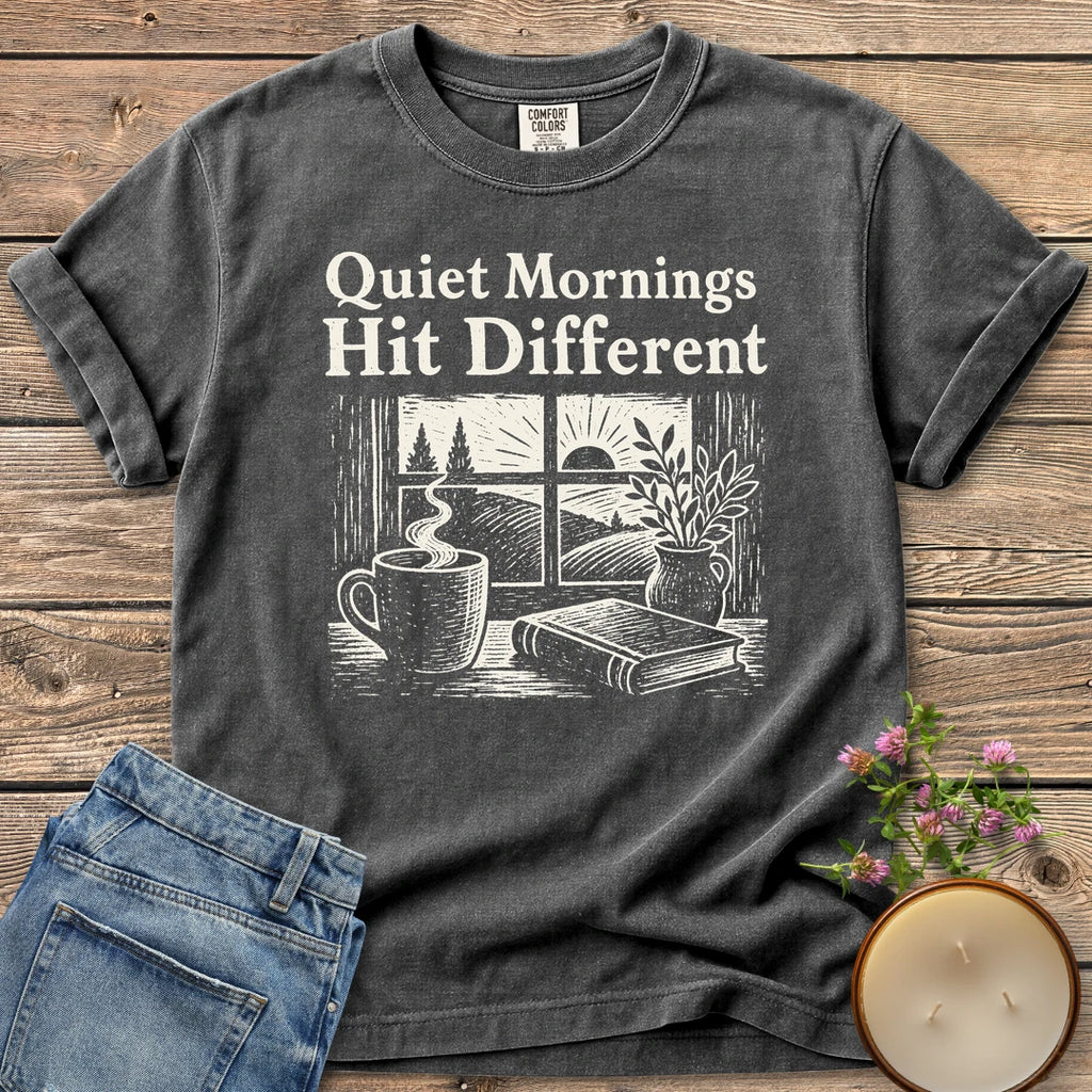 Quiet Mornings Hit Different t-shirt, Quiet Mornings Hit Different over a woodcut of coffee, a book and a window at sunrise, on a Pepper Comfort Colors tee