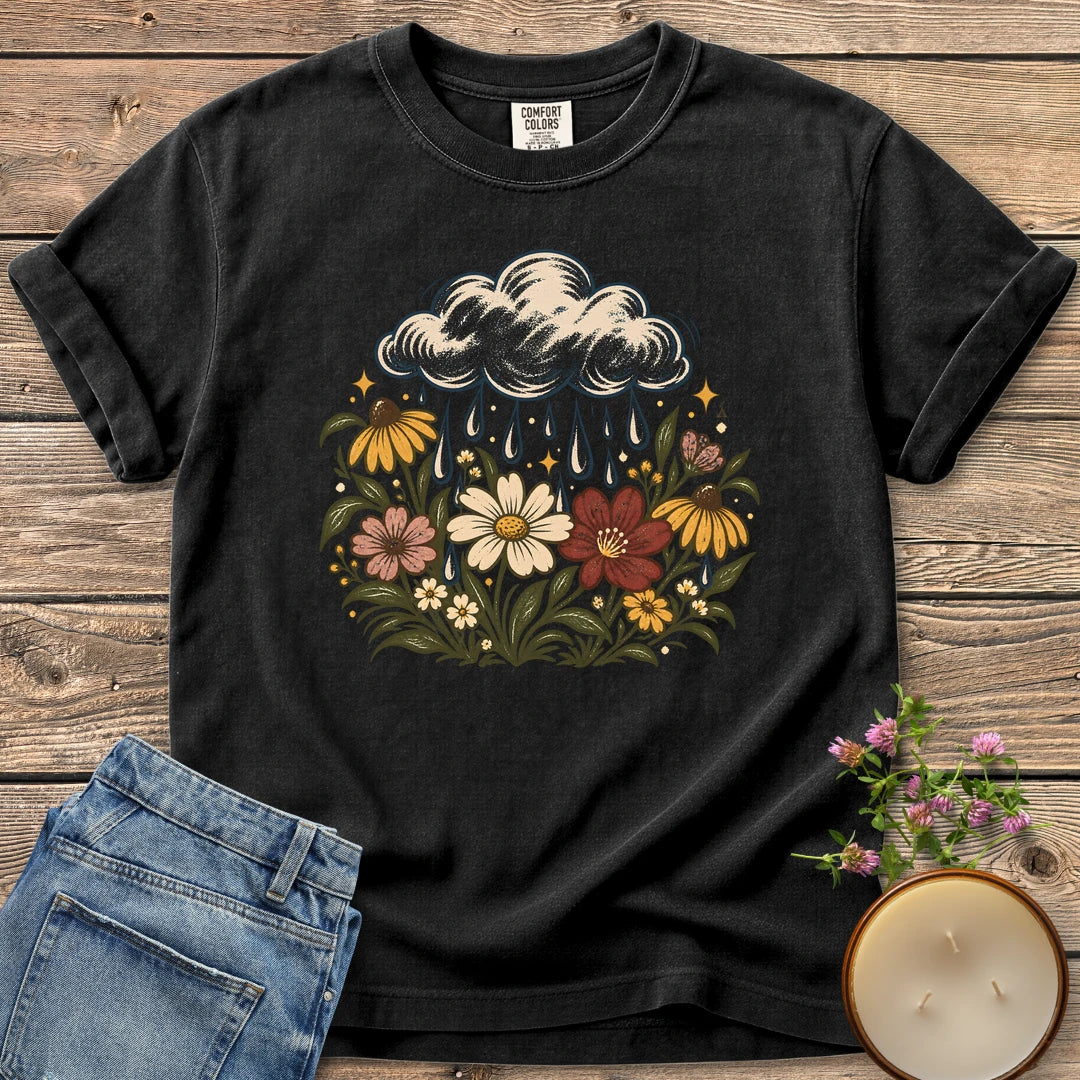 Rain Cloud Wildflower Meadow t-shirt, a rain cloud watering a colorful wildflower meadow, on a Black Comfort Colors tee