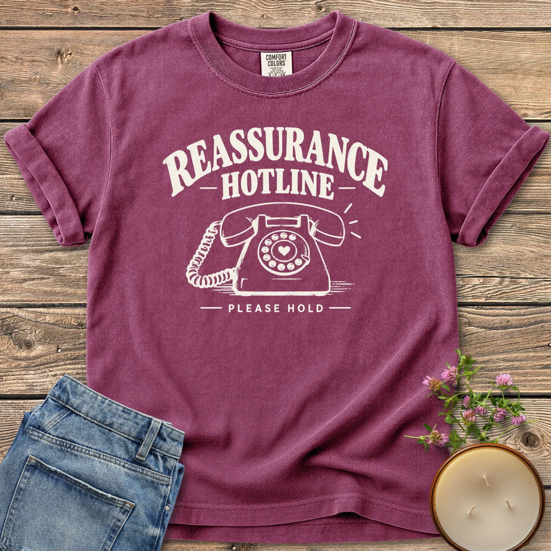 Reassurance Hotline Please Hold t-shirt, Reassurance Hotline above a rotary phone with a heart dial and Please Hold, on a Berry Comfort Colors tee
