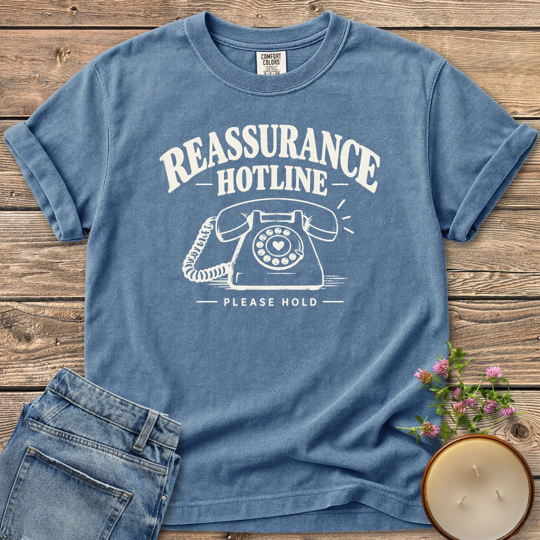Reassurance Hotline Please Hold t-shirt, Reassurance Hotline above a rotary phone with a heart dial and Please Hold, on a Blue Jean Comfort Colors tee