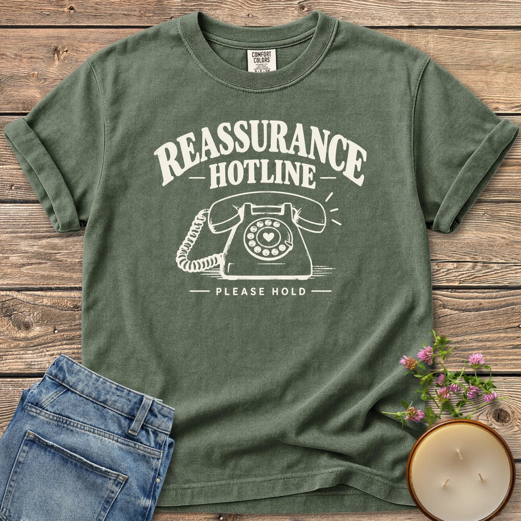 Reassurance Hotline Please Hold t-shirt, Reassurance Hotline above a rotary phone with a heart dial and Please Hold, on a Moss Comfort Colors tee