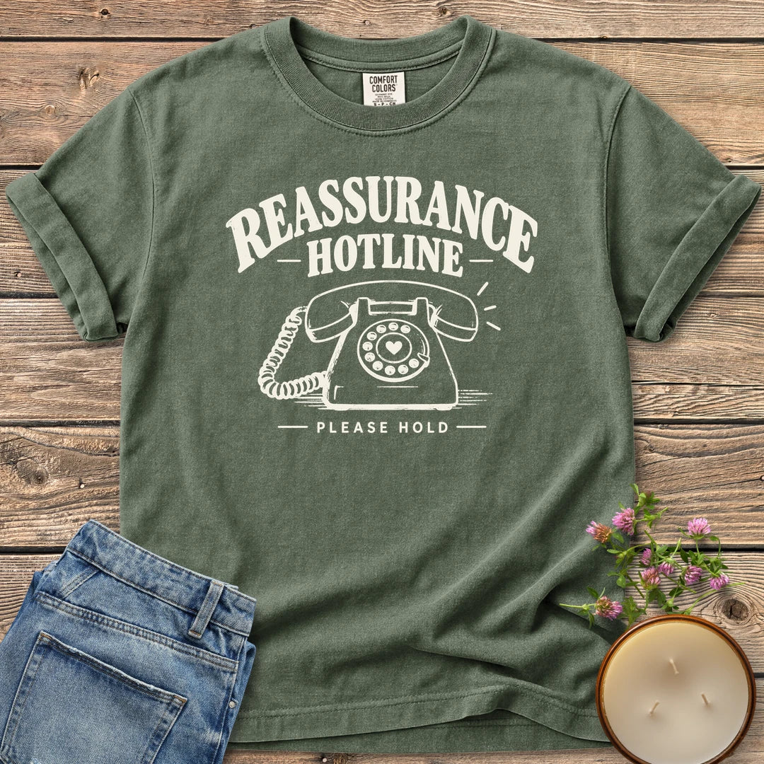 Reassurance Hotline Please Hold t-shirt, Reassurance Hotline above a rotary phone with a heart dial and Please Hold, on a Moss Comfort Colors tee