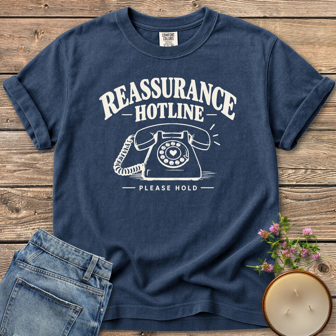 Reassurance Hotline Please Hold t-shirt, Reassurance Hotline above a rotary phone with a heart dial and Please Hold, on a Navy Comfort Colors tee