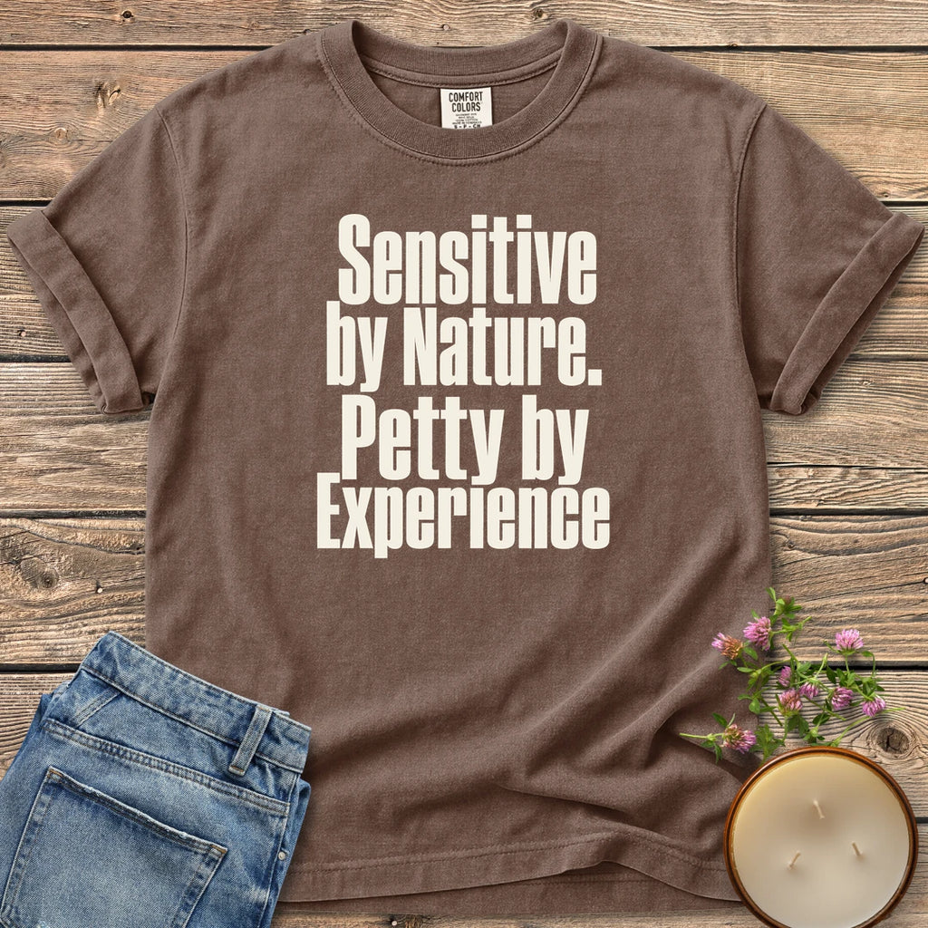 Sensitive by Nature t-shirt, Sensitive by Nature. Petty by Experience. in bold condensed type, on an Espresso Comfort Colors tee