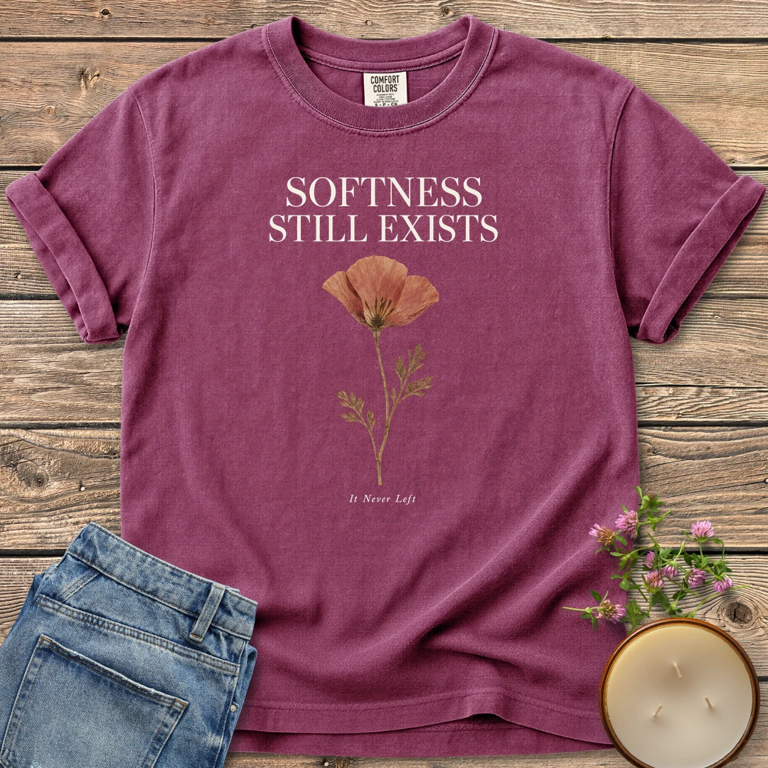 Softness Still Exists t-shirt, Softness Still Exists above a pressed poppy and It Never Left, on a Berry Comfort Colors tee