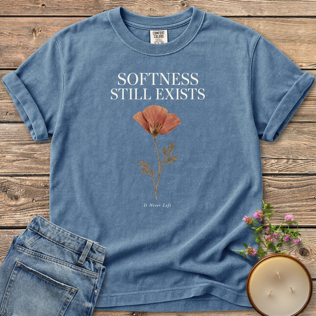 Softness Still Exists t-shirt, Softness Still Exists above a pressed poppy and It Never Left, on a Blue Jean Comfort Colors tee