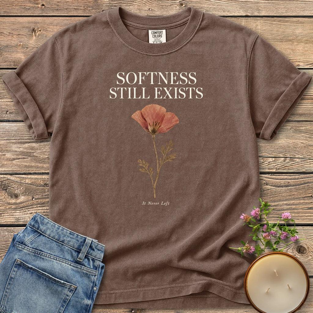 Softness Still Exists t-shirt, Softness Still Exists above a pressed poppy and It Never Left, on an Espresso Comfort Colors tee