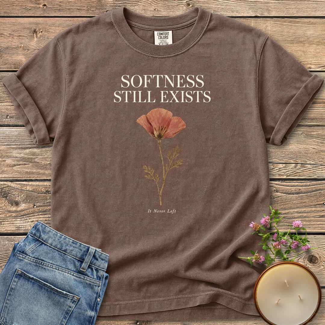 Softness Still Exists t-shirt, Softness Still Exists above a pressed poppy and It Never Left, on an Espresso Comfort Colors tee