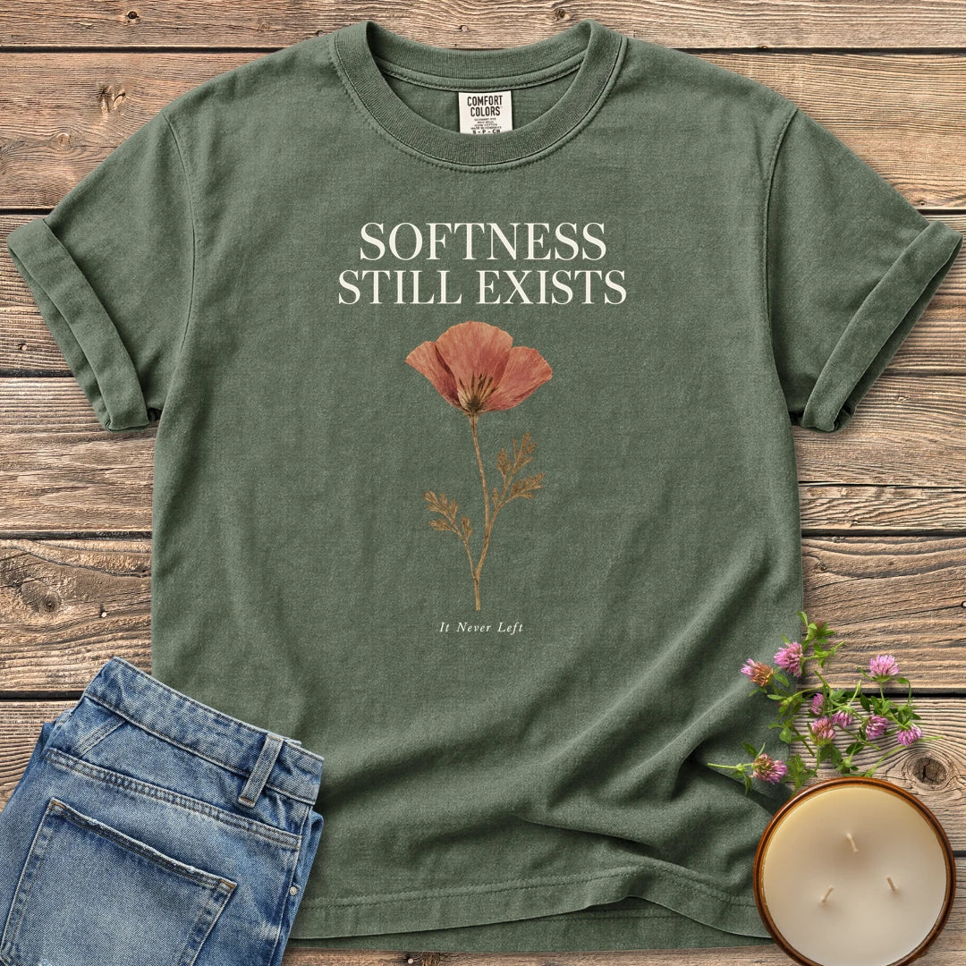 Softness Still Exists t-shirt, Softness Still Exists above a pressed poppy and It Never Left, on a Moss Comfort Colors tee