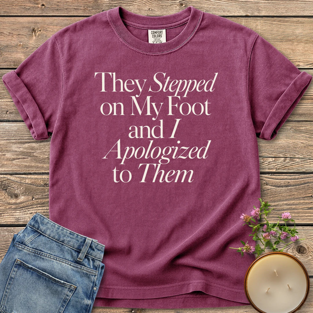 Stepped on My Foot t-shirt, They Stepped on My Foot and I Apologized to Them in serif and italic type, on a Berry Comfort Colors tee