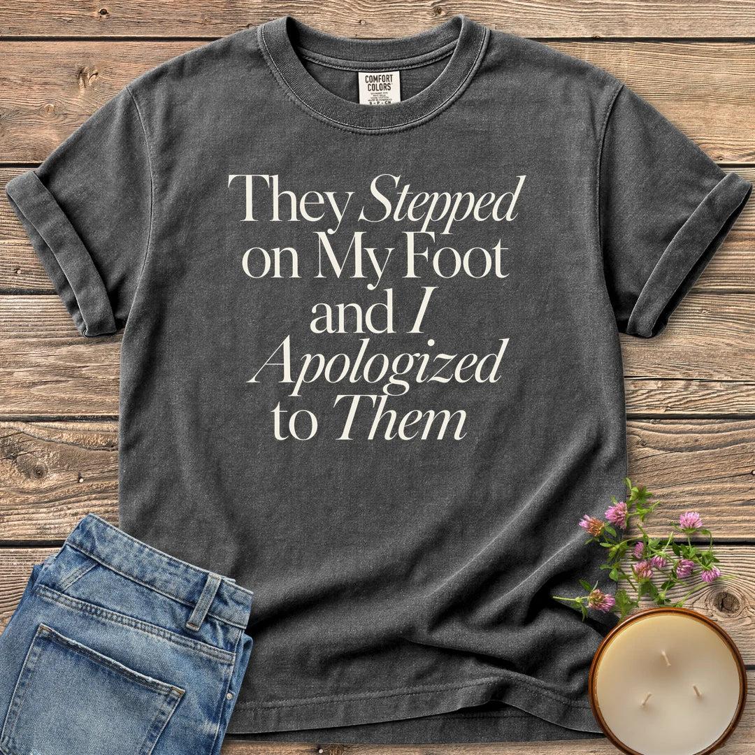 Stepped on My Foot t-shirt, They Stepped on My Foot and I Apologized to Them in serif and italic type, on a Pepper Comfort Colors tee