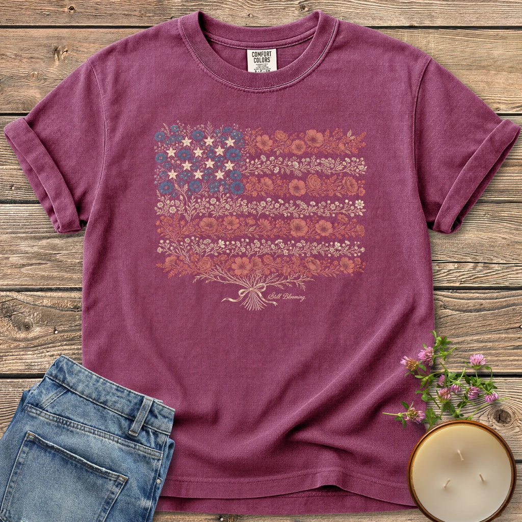 Still Blooming t-shirt, an American flag made of wildflowers with Still Blooming in script, on a Berry Comfort Colors tee