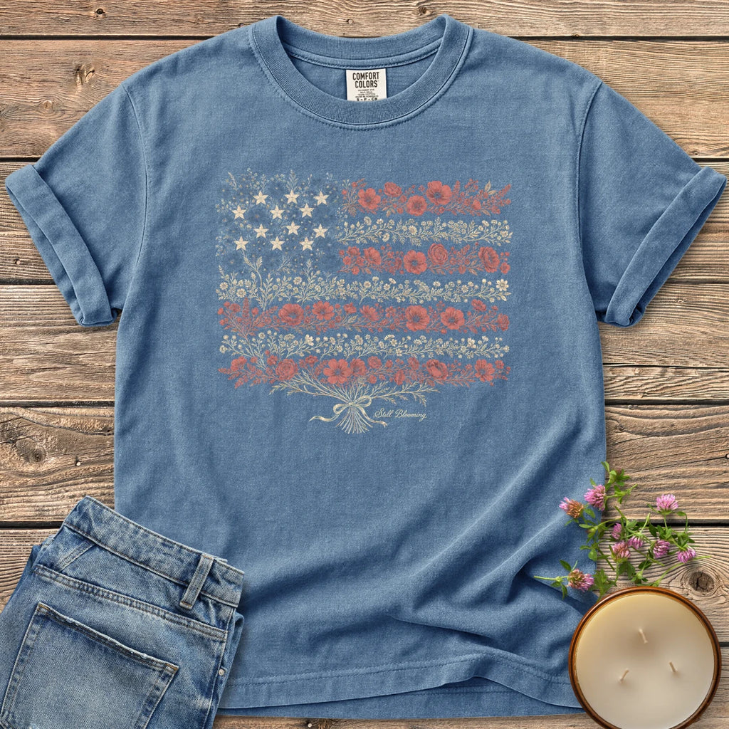 Still Blooming t-shirt, an American flag made of wildflowers with Still Blooming in script, on a Blue Jean Comfort Colors tee