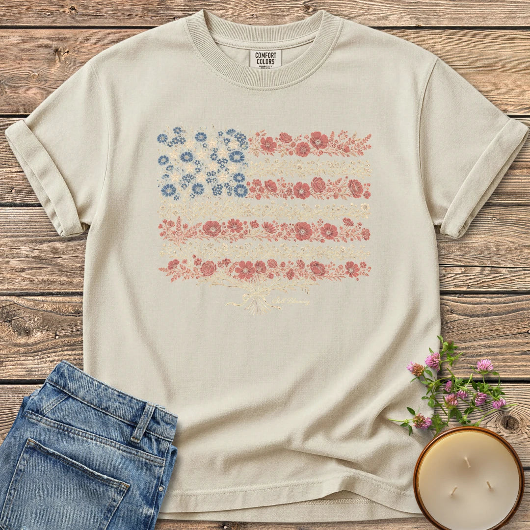 Still Blooming t-shirt, an American flag made of wildflowers with Still Blooming in script, on an Ivory Comfort Colors tee