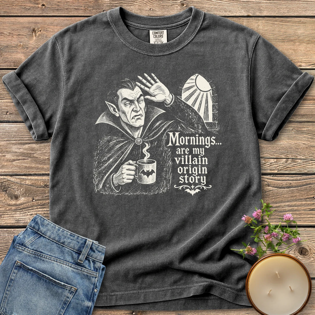 Villain Origin Story t-shirt, a vampire shielding his eyes from sunlight holding a coffee mug with Mornings... are my villain origin story, on a Pepper Comfort Colors tee