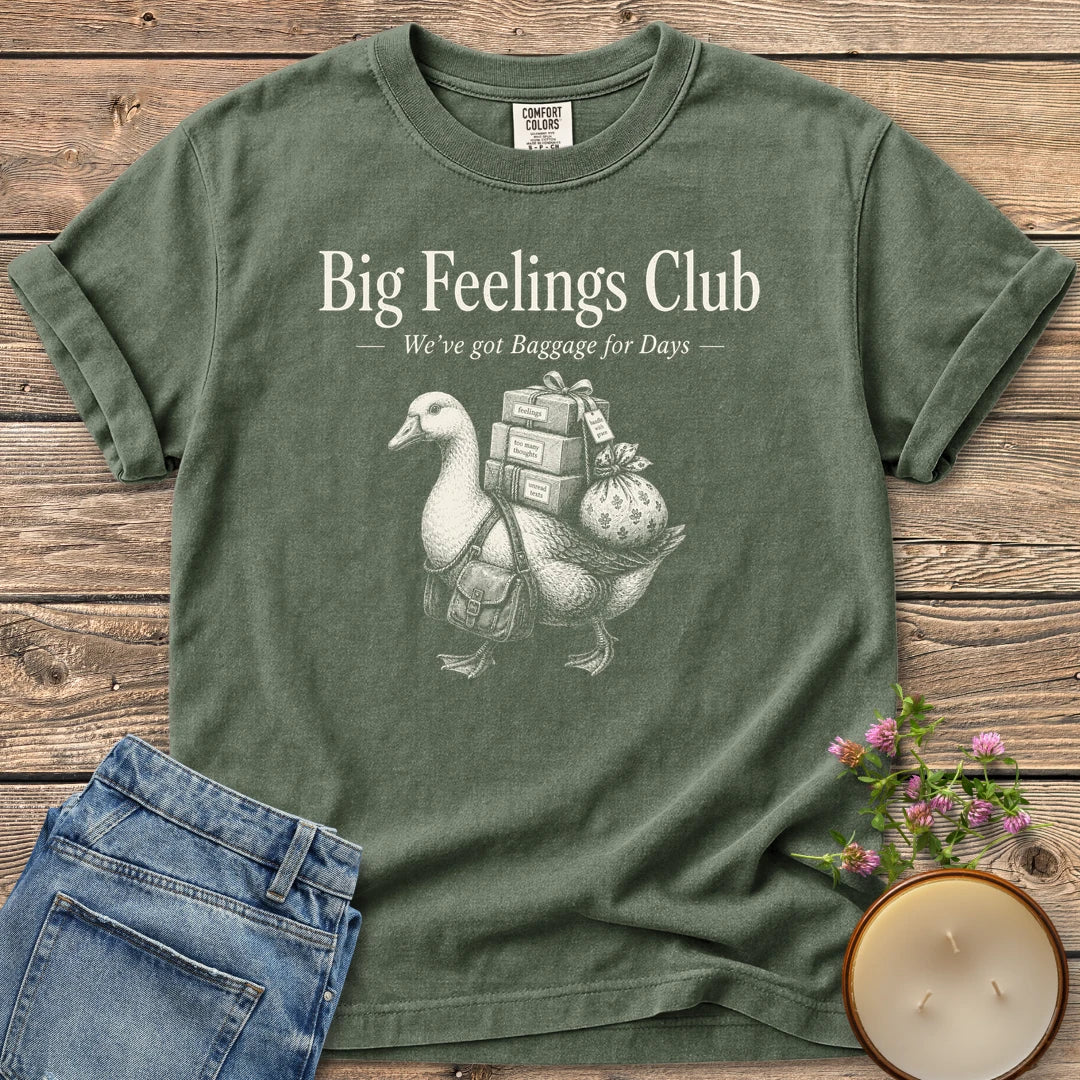We've Got Baggage for Days t-shirt, a goose carrying boxes of feelings, too many thoughts and unread texts under Big Feelings Club, We've got Baggage for Days, on a Moss Comfort Colors tee