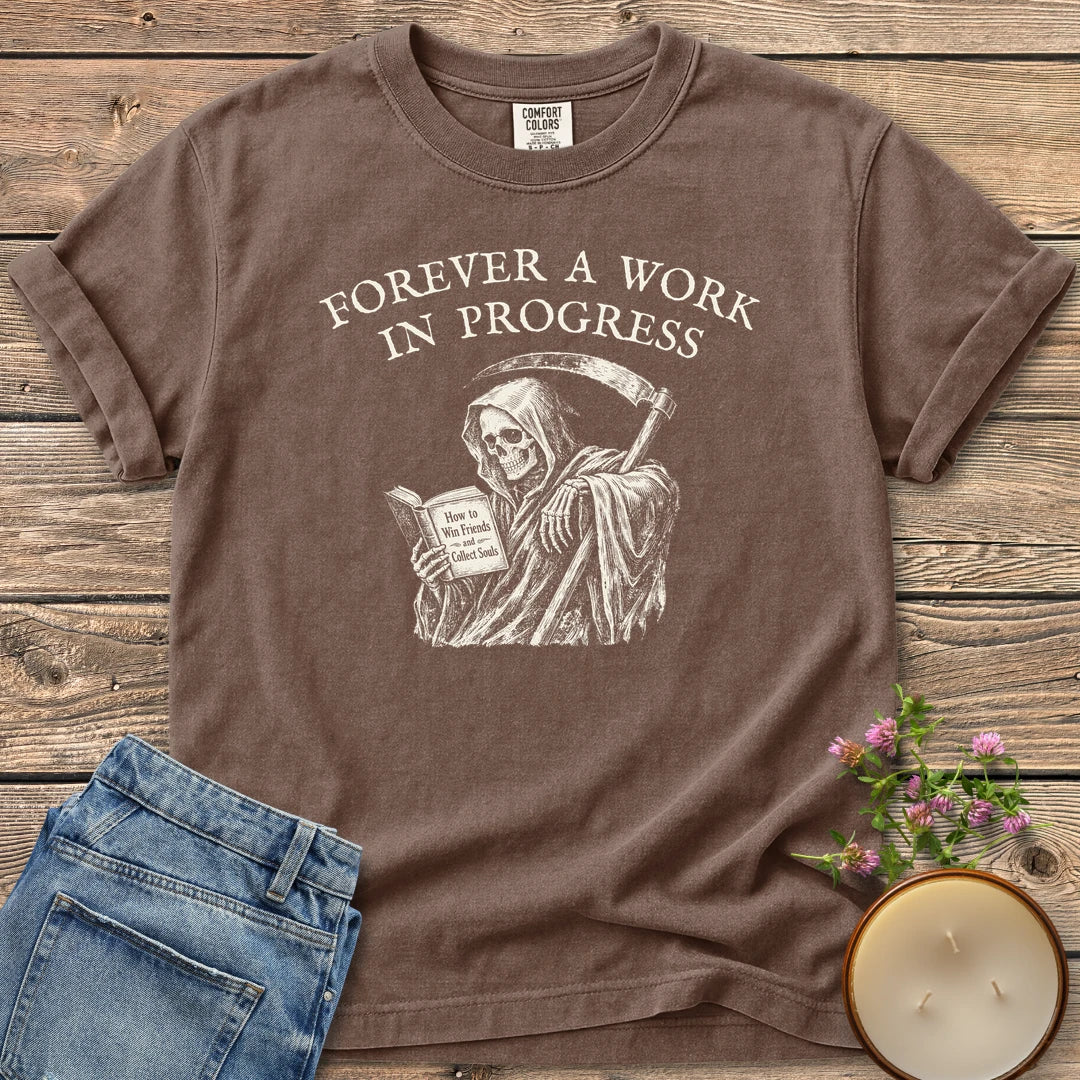 Win Friends Collect Souls t-shirt, a grim reaper reading How to Win Friends and Collect Souls under Forever A Work In Progress, on an Espresso Comfort Colors tee